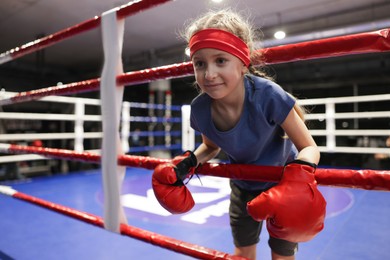 Photo of Girl in protective gloves on boxing ring. Space for text