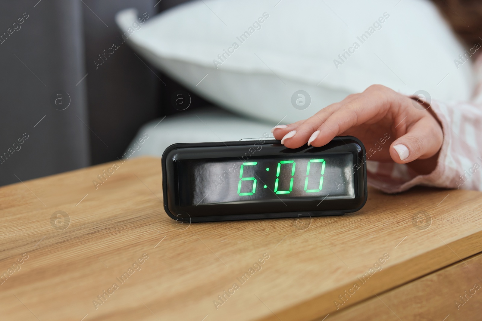 Woman turning off digital alarm clock on bedside table indoors, closeup Photo of Woman turning off digital alarm clock on bedside table indoors, closeup