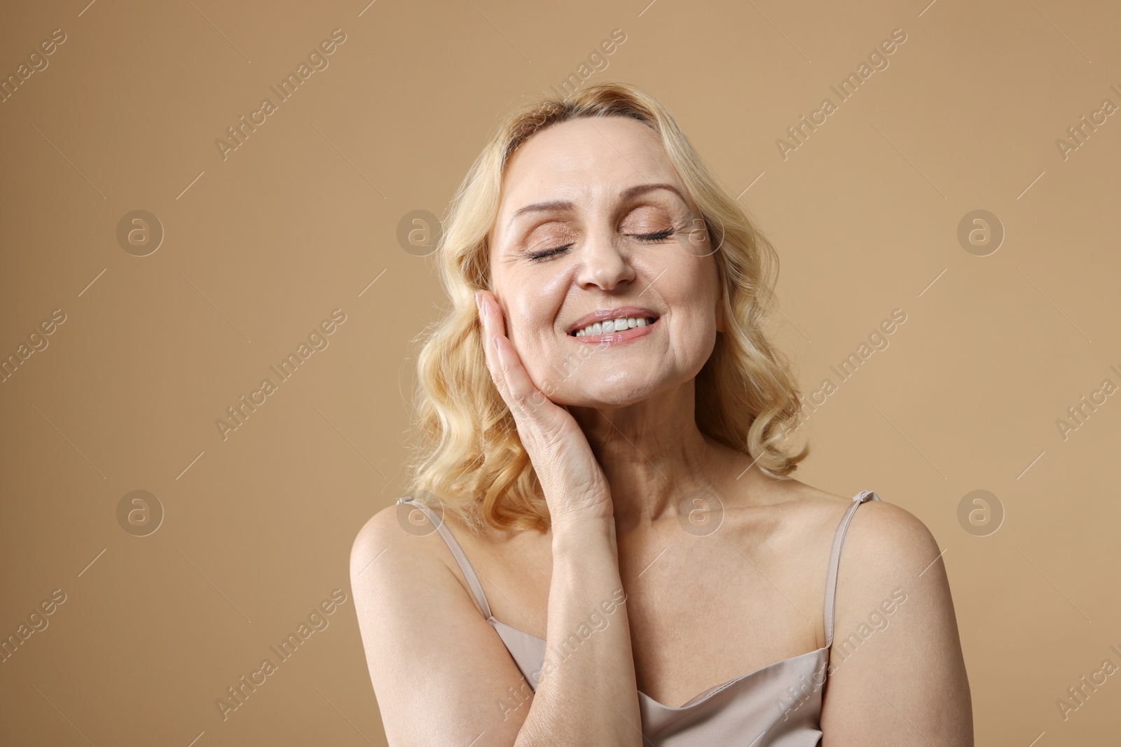 Photo of Smiling middle aged woman on beige background. Space for text