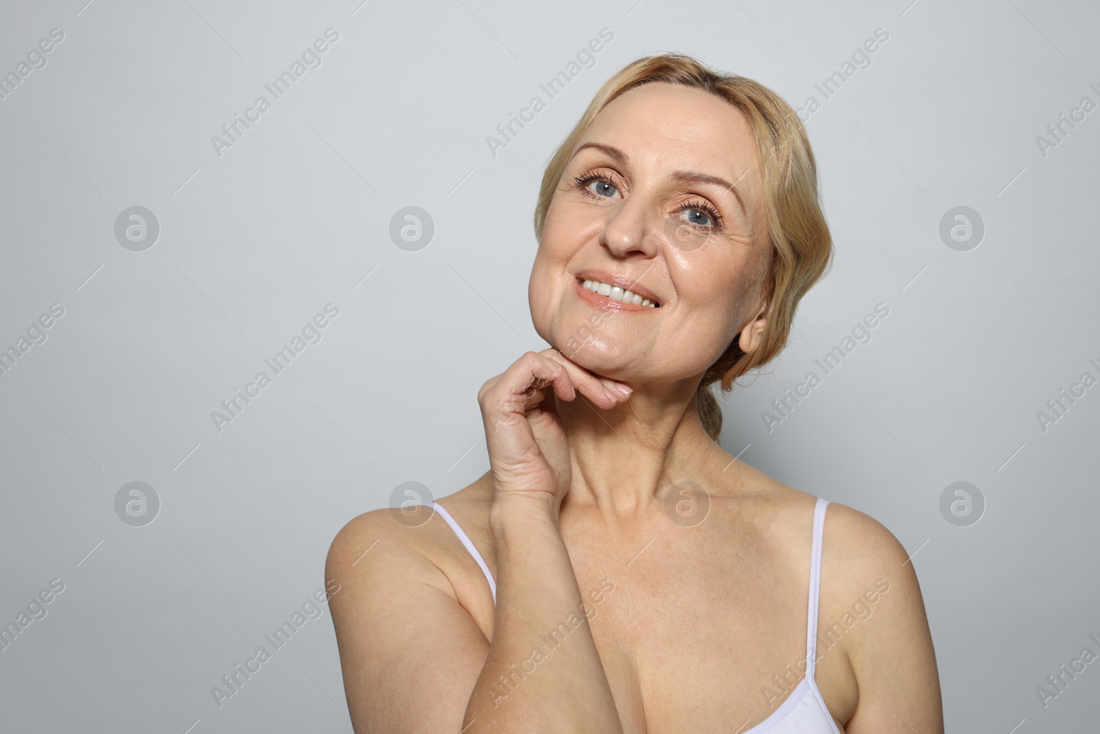 Photo of Smiling middle aged woman on grey background. Space for text