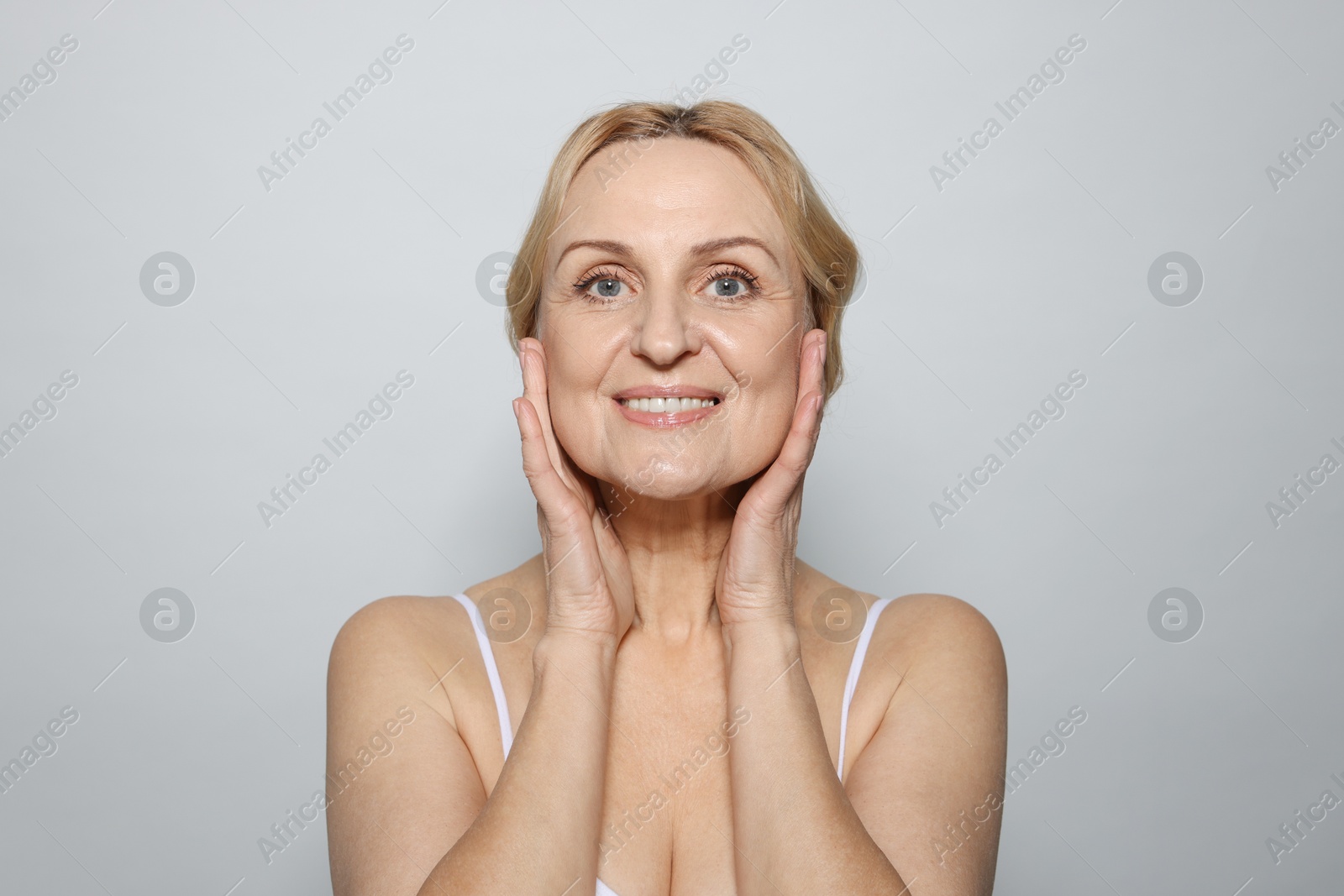 Photo of Portrait of smiling middle aged woman on grey background