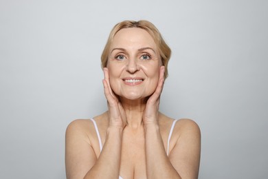 Photo of Portrait of smiling middle aged woman on grey background