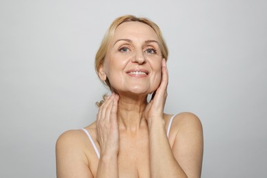 Portrait of smiling middle aged woman on grey background