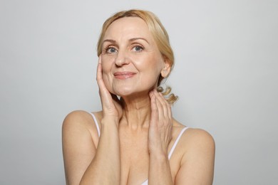 Portrait of beautiful middle aged woman on grey background