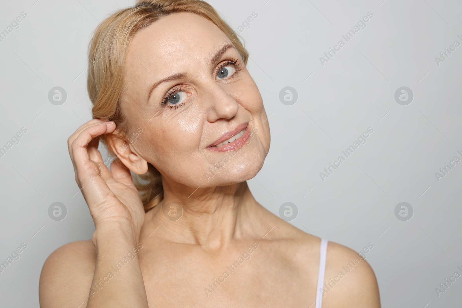 Photo of Portrait of smiling middle aged woman on grey background