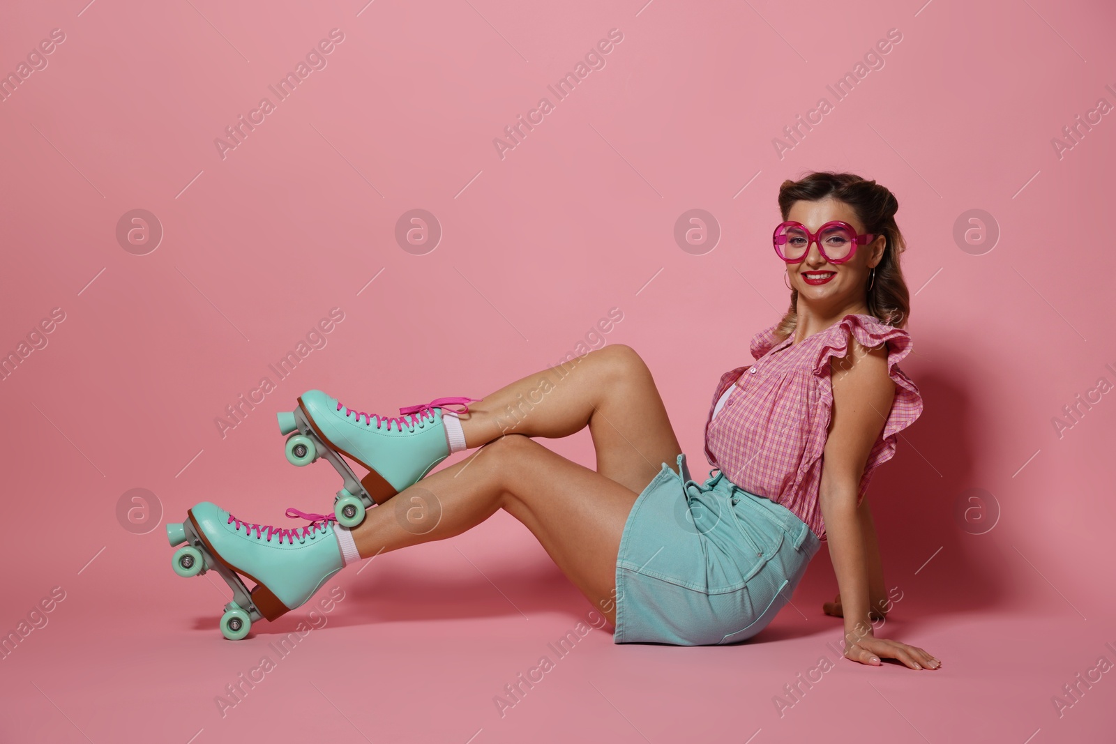 Photo of Happy pin-up woman in roller skates posing on pink background