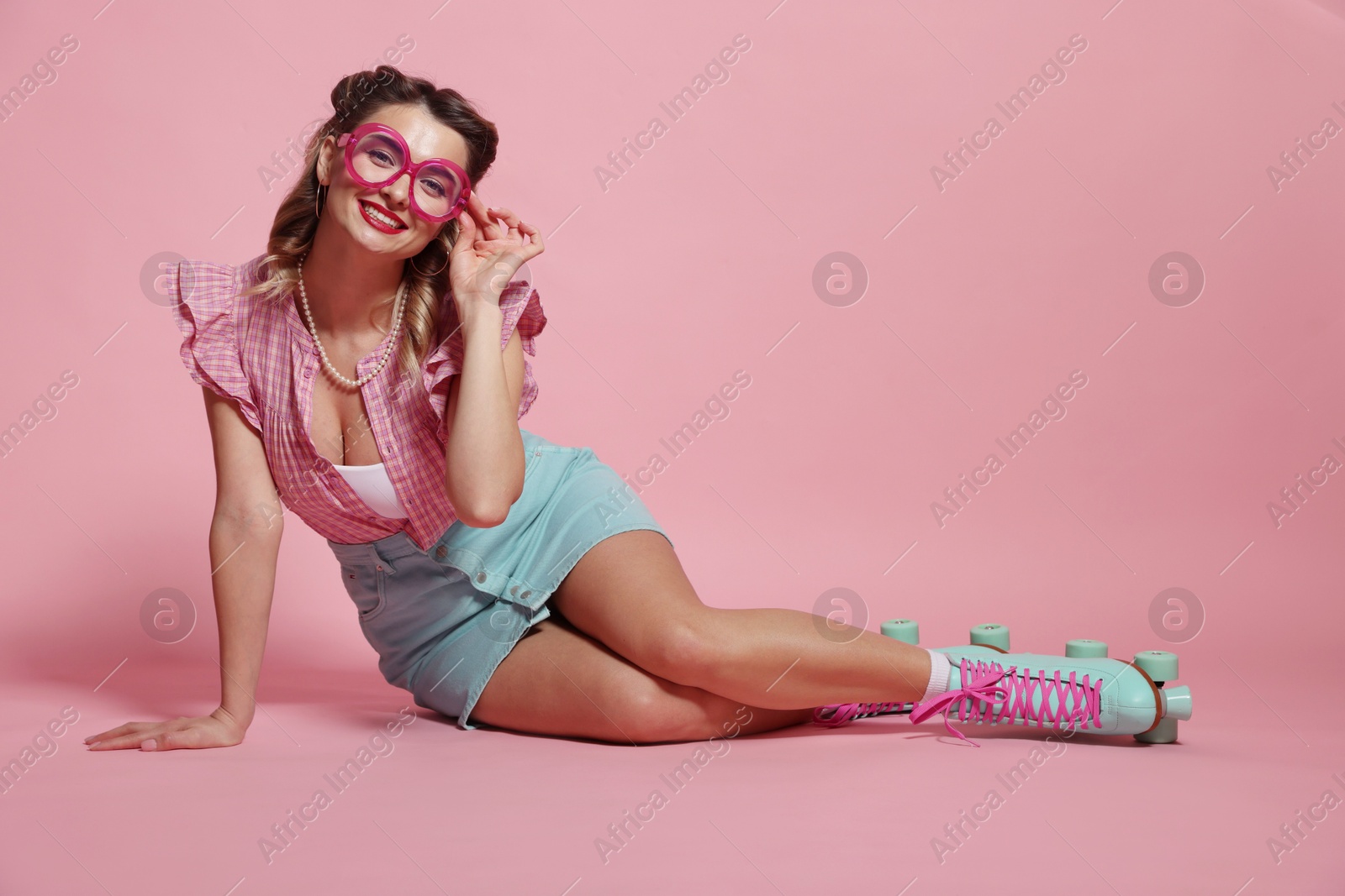 Photo of Happy pin-up woman in roller skates posing on pink background, space for text