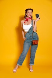 Happy woman with vintage camera on orange background. Pin-up vibes