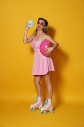 Photo of Happy woman with camera and inflatable ball on orange background. Pin-up vibes