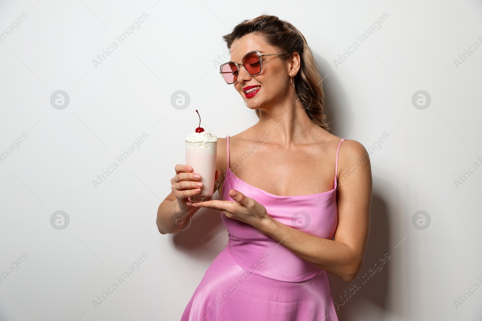 Photo of Happy woman with milk shake on light background. Pin-up vibe portrait