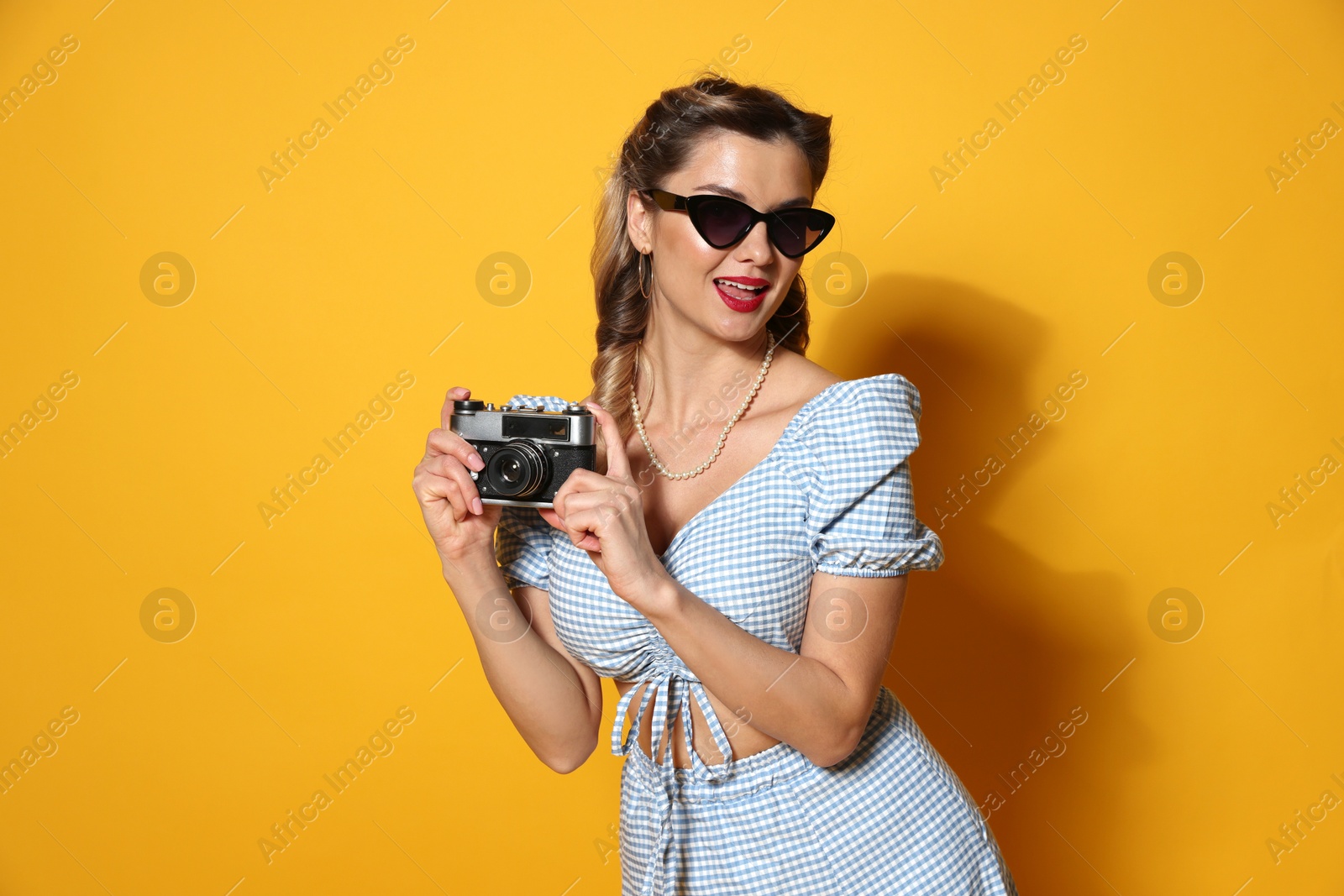 Photo of Happy pin-up woman with camera on orange background