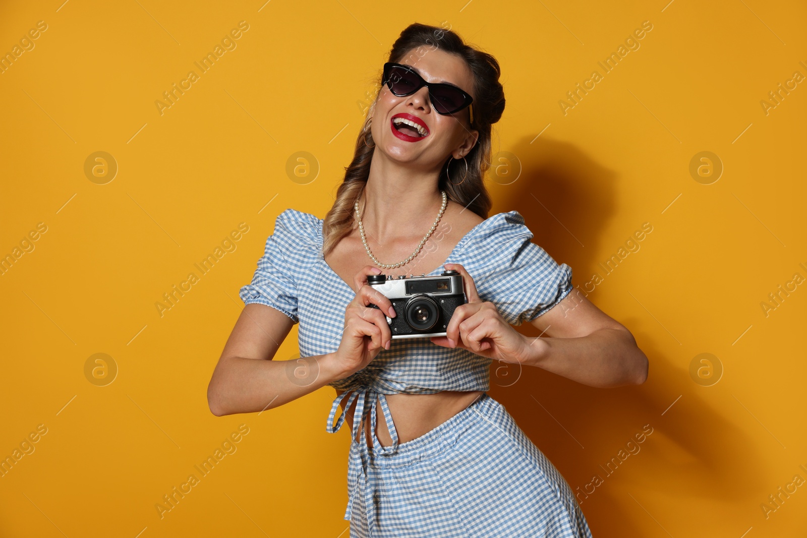 Photo of Happy pin-up woman with camera on orange background