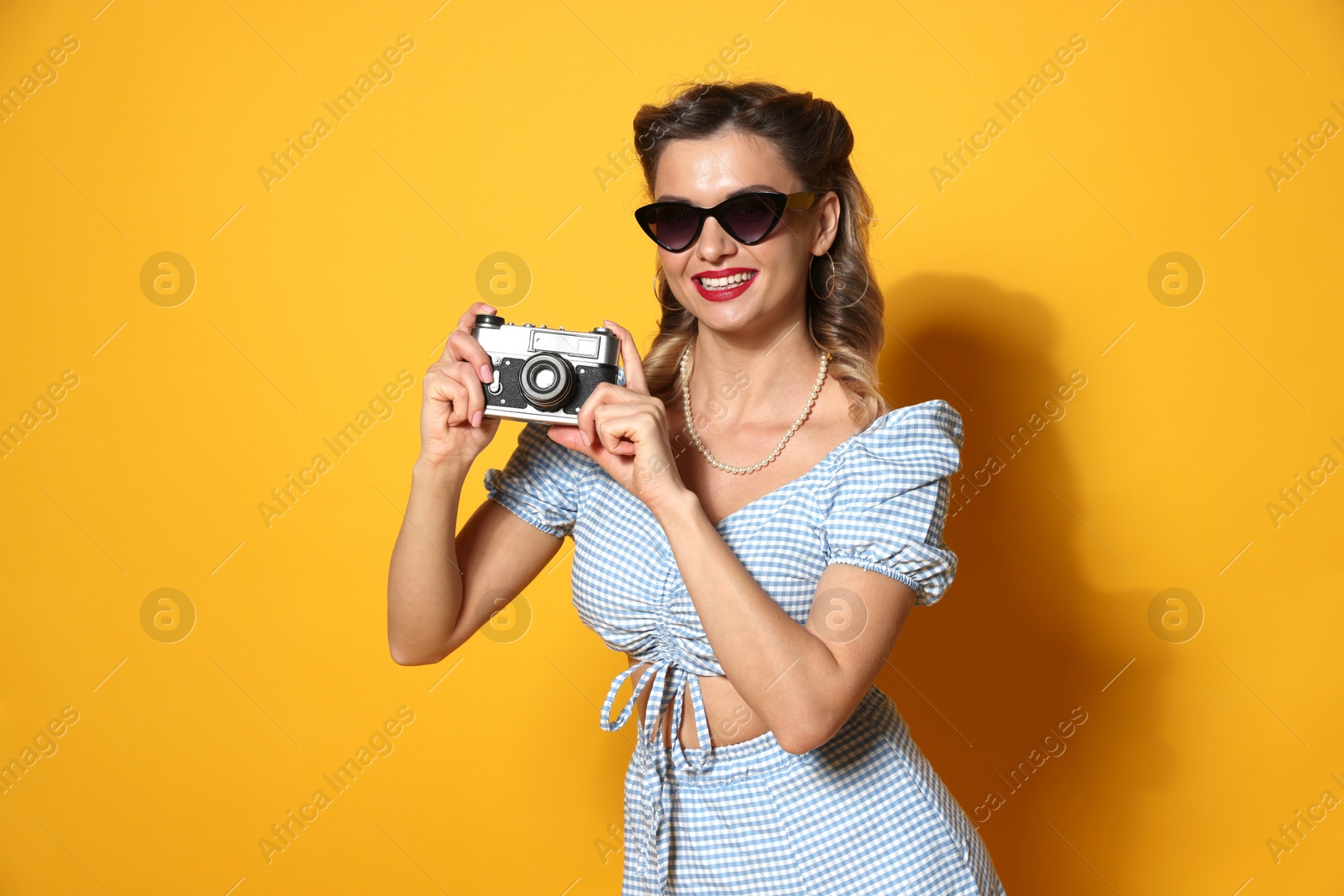 Photo of Happy pin-up woman with camera on orange background