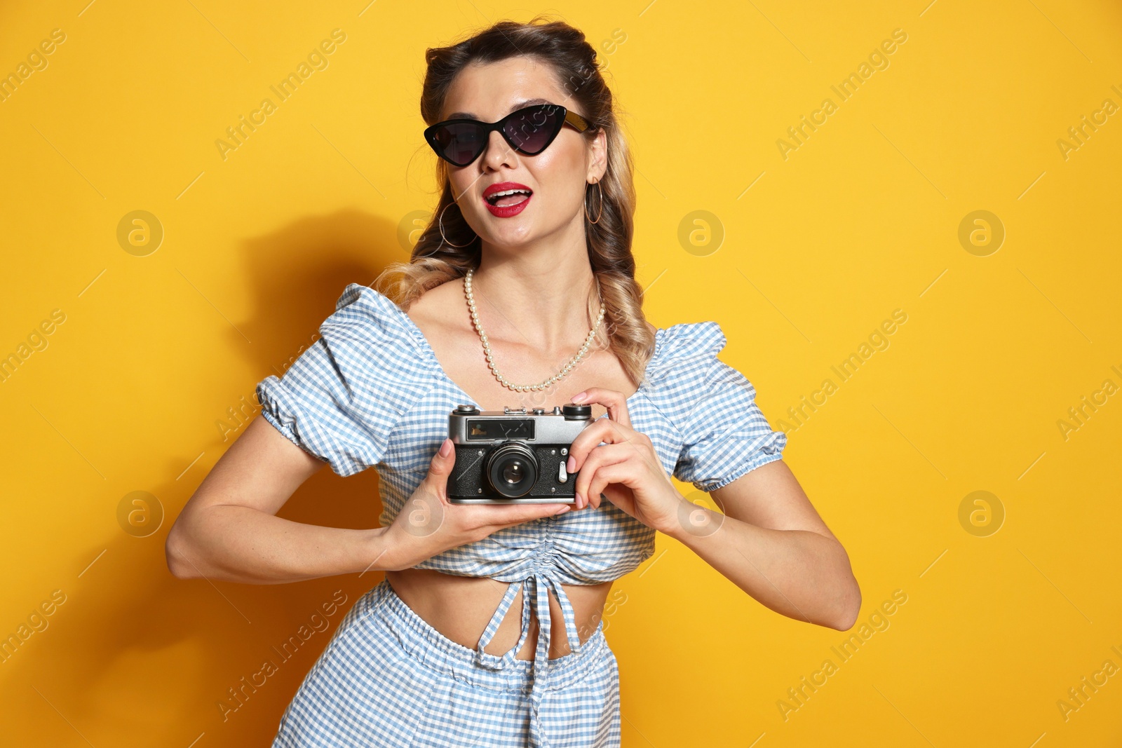 Photo of Beautiful pin-up woman with camera on orange background