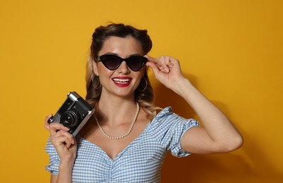 Photo of Happy pin-up woman with camera on orange background