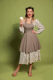 Happy woman with cupcake on green background. Pin-up vibes