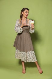 Photo of Happy woman with cupcake on green background. Pin-up vibes