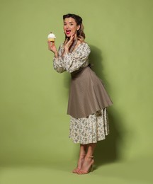 Photo of Happy woman with cupcake on green background. Pin-up vibes