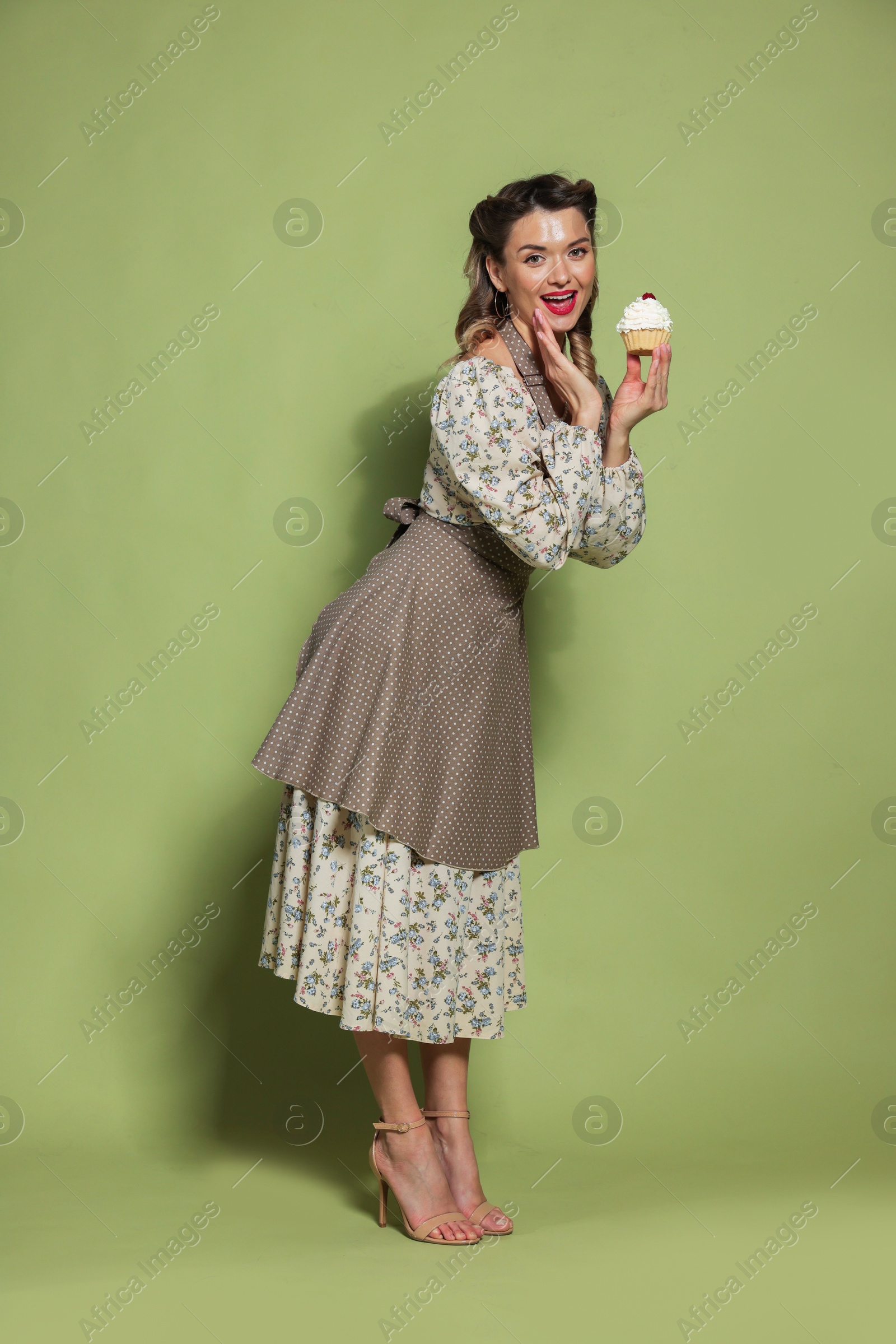 Photo of Happy woman with cupcake on green background. Pin-up vibes