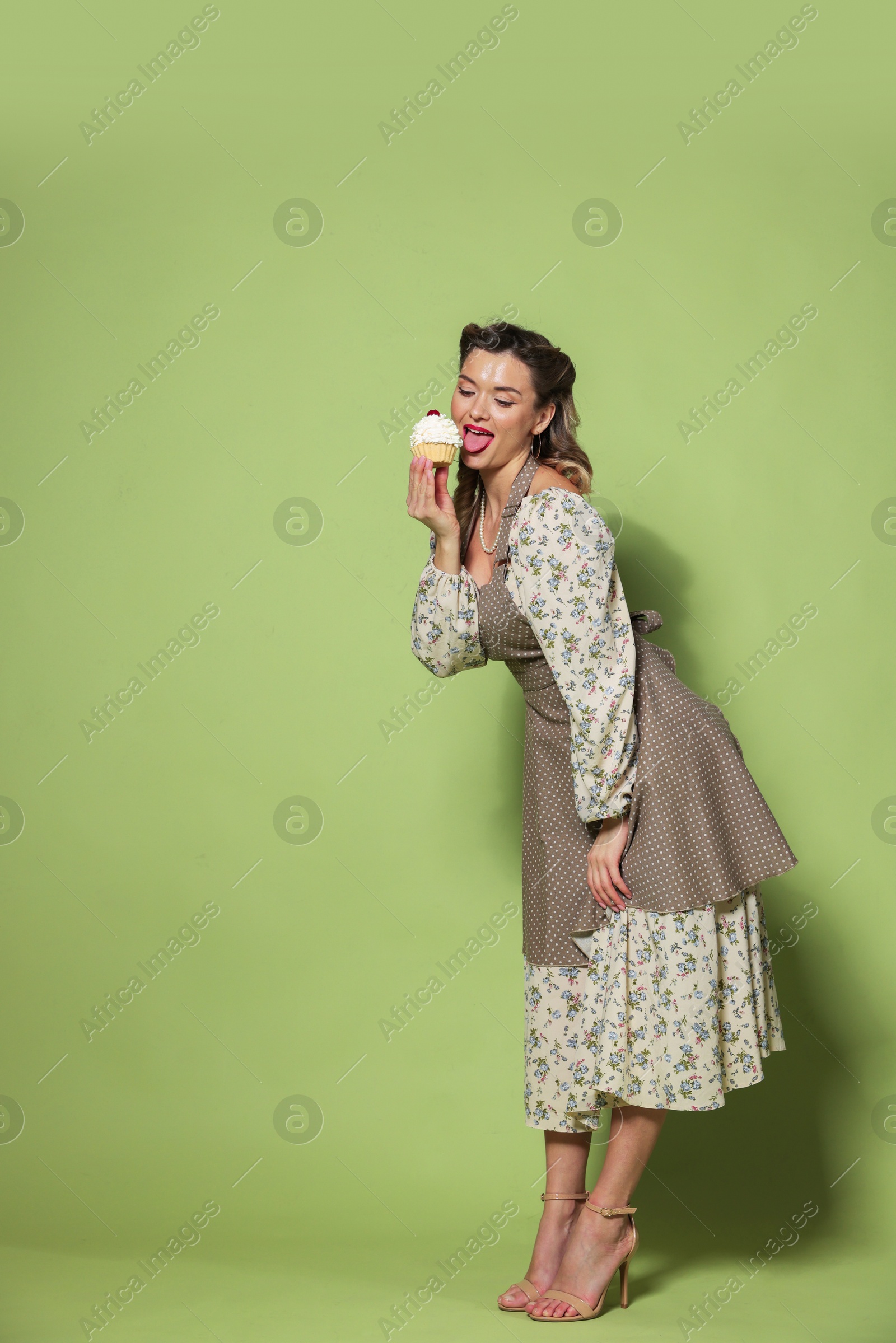 Photo of Beautiful woman with cupcake on green background. Pin-up vibes