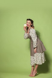 Photo of Beautiful woman with cupcake on green background. Pin-up vibes