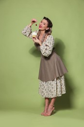 Beautiful woman with cupcake on green background. Pin-up vibes