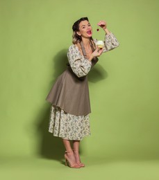 Photo of Beautiful woman with cupcake on green background. Pin-up vibes