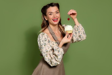 Photo of Happy woman with cupcake and cherry on green background. Pin-up vibe portrait