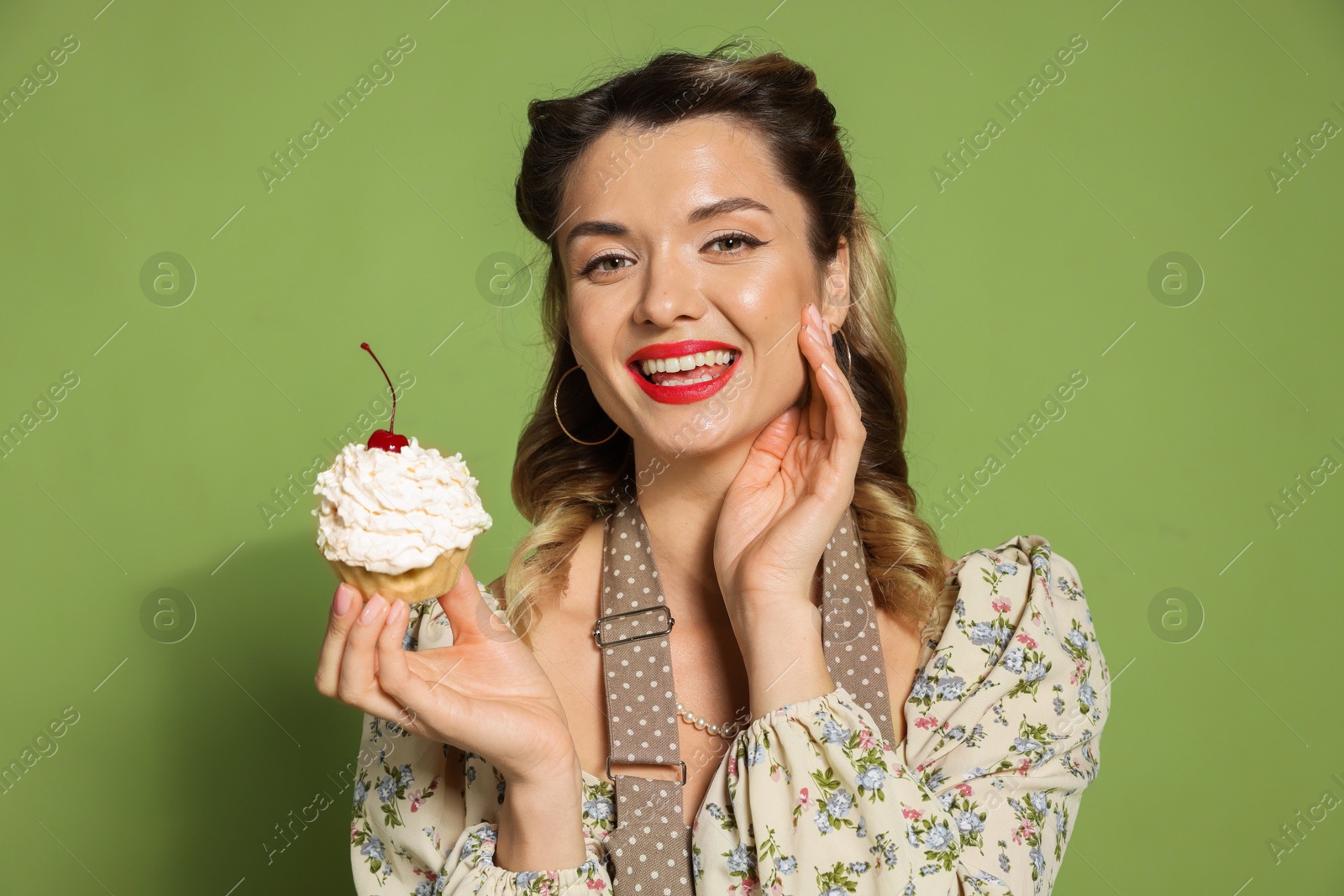 Photo of Happy woman with cupcake on green background. Pin-up vibe portrait