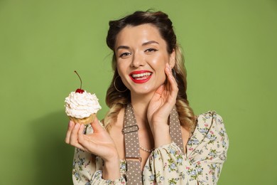 Happy woman with cupcake on green background. Pin-up vibe portrait