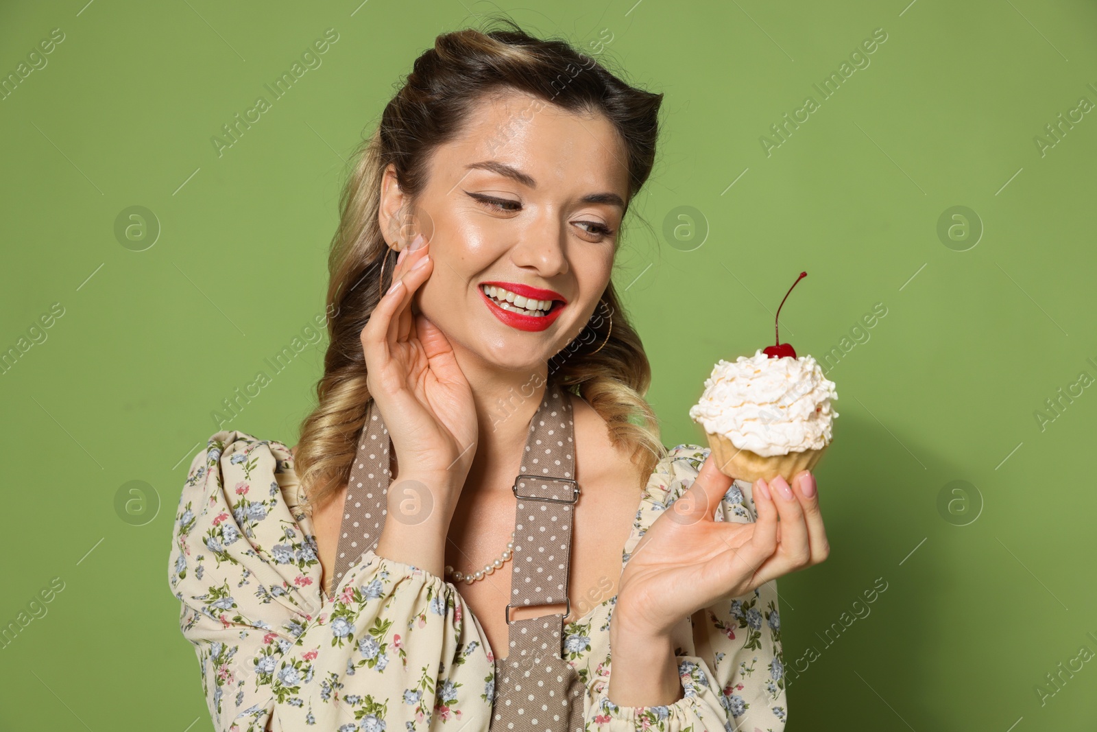 Photo of Happy woman with cupcake on green background. Pin-up vibe portrait