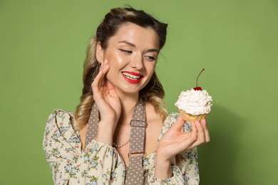 Happy woman with cupcake on green background. Pin-up vibe portrait