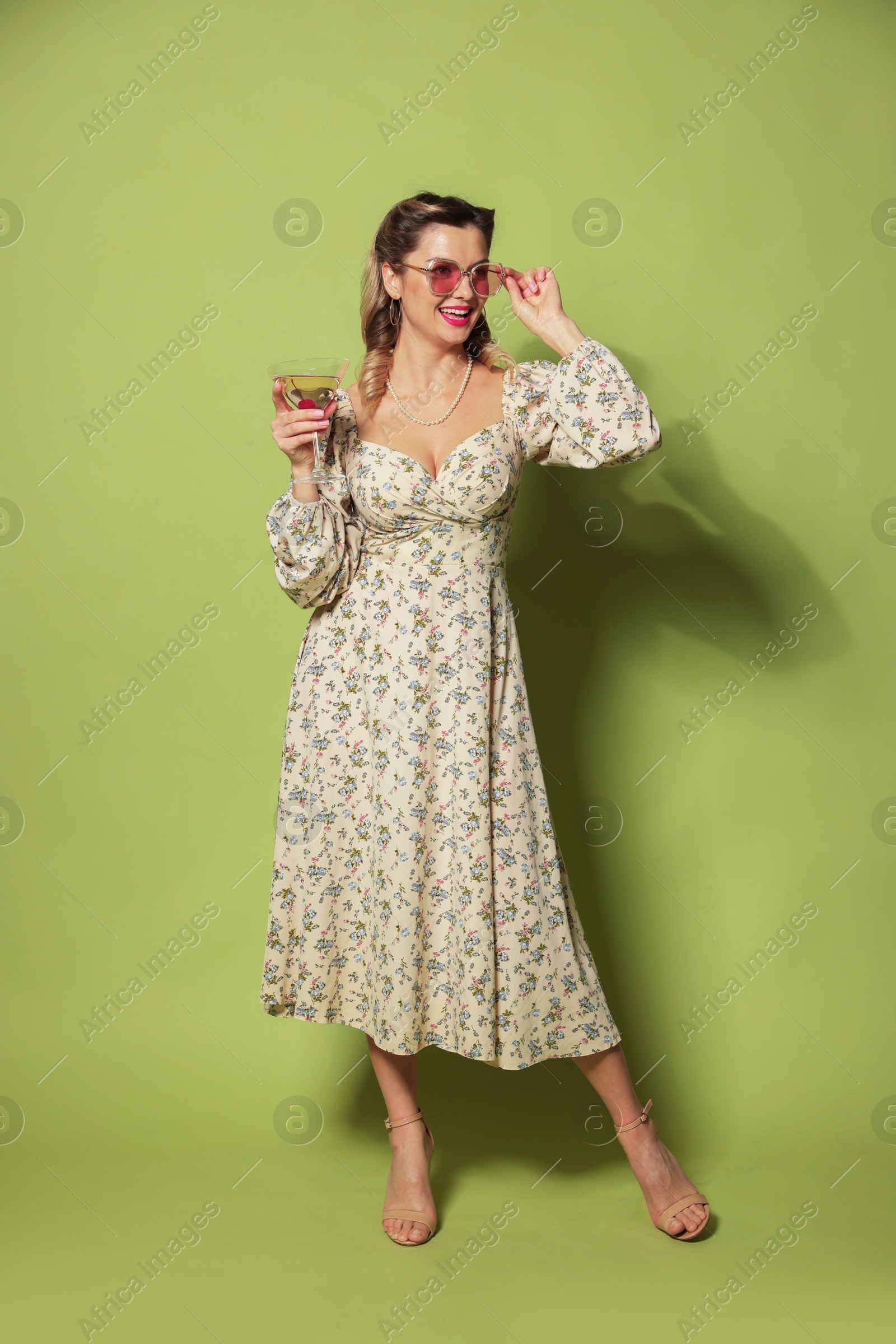 Photo of Happy woman with cocktail on green background. Pin-up vibes