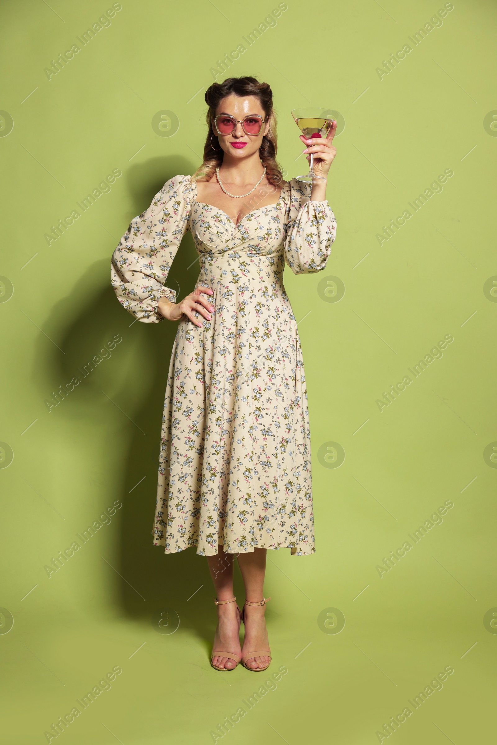 Photo of Beautiful woman with cocktail on green background. Pin-up vibes