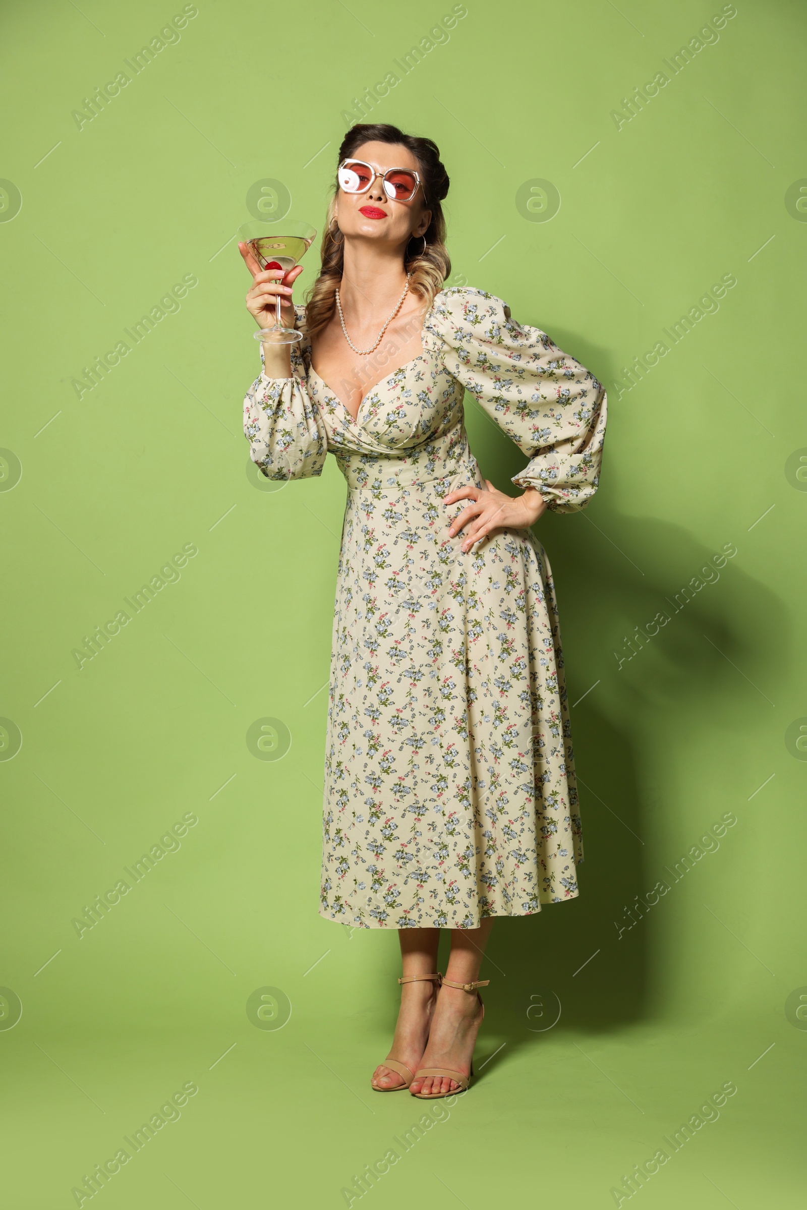 Photo of Beautiful woman with cocktail on green background. Pin-up vibes