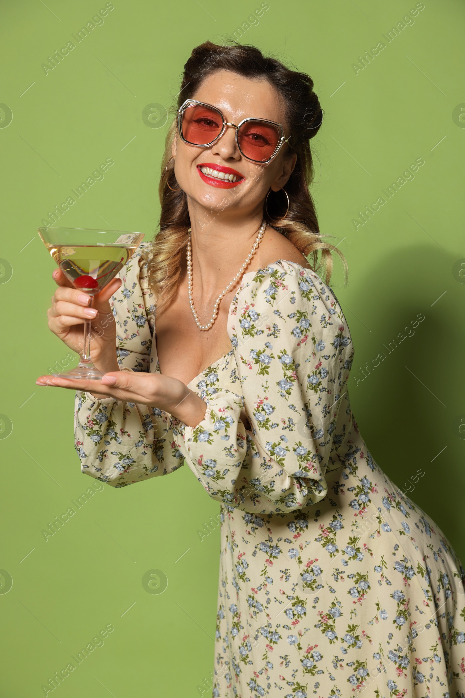 Photo of Happy woman with cocktail on green background. Pin-up vibes