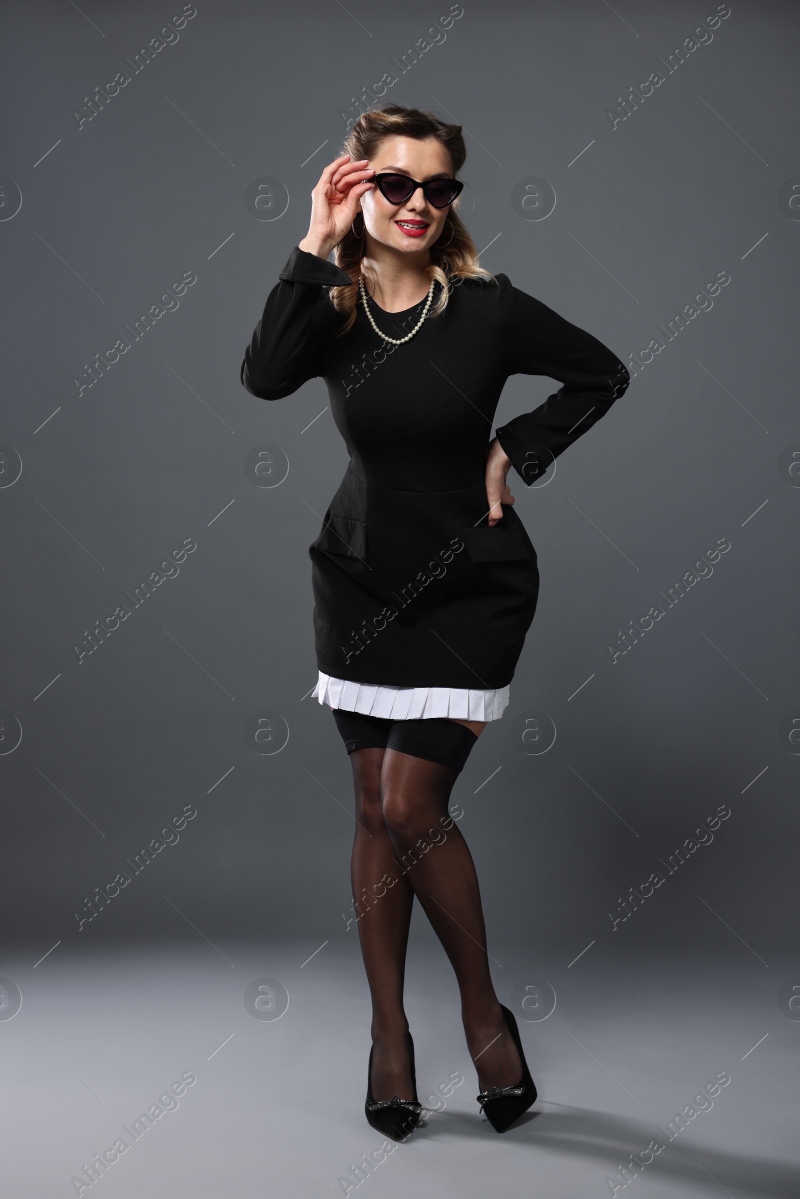 Photo of Happy pin-up woman posing on grey background