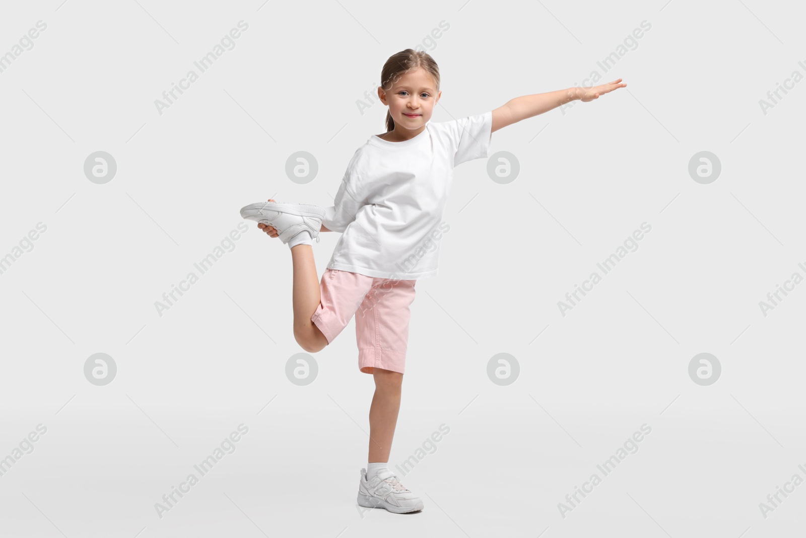 Photo of Cute little girl exercising on white background