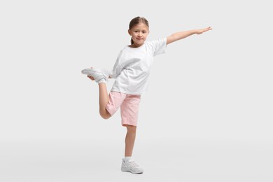 Photo of Cute little girl exercising on white background