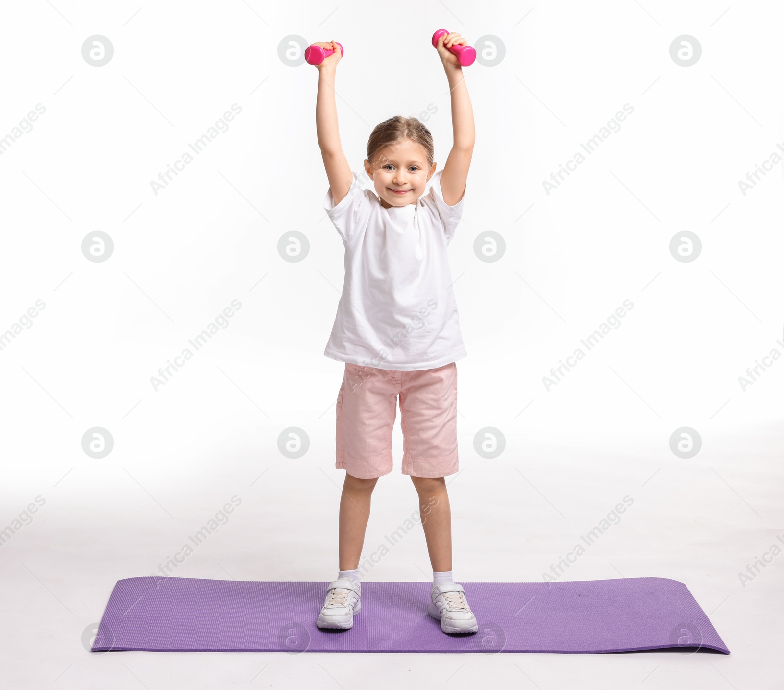 Photo of Little girl exercising with dumbbells on white background