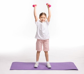 Little girl exercising with dumbbells on white background