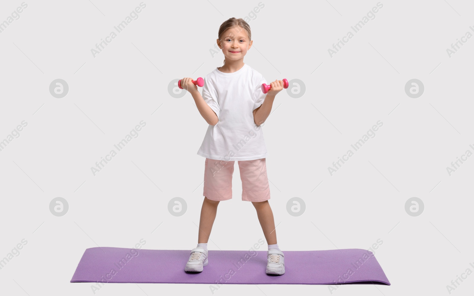 Photo of Little girl exercising with dumbbells on white background