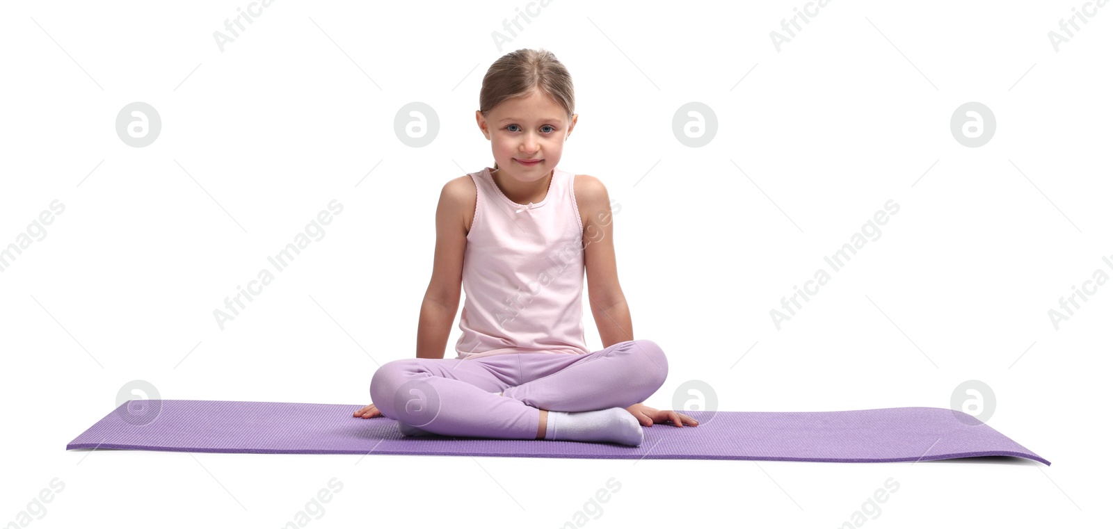 Photo of Little girl in sportswear sitting on fitness mat against white background