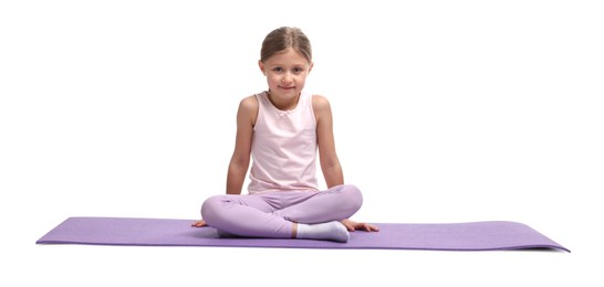 Little girl in sportswear sitting on fitness mat against white background