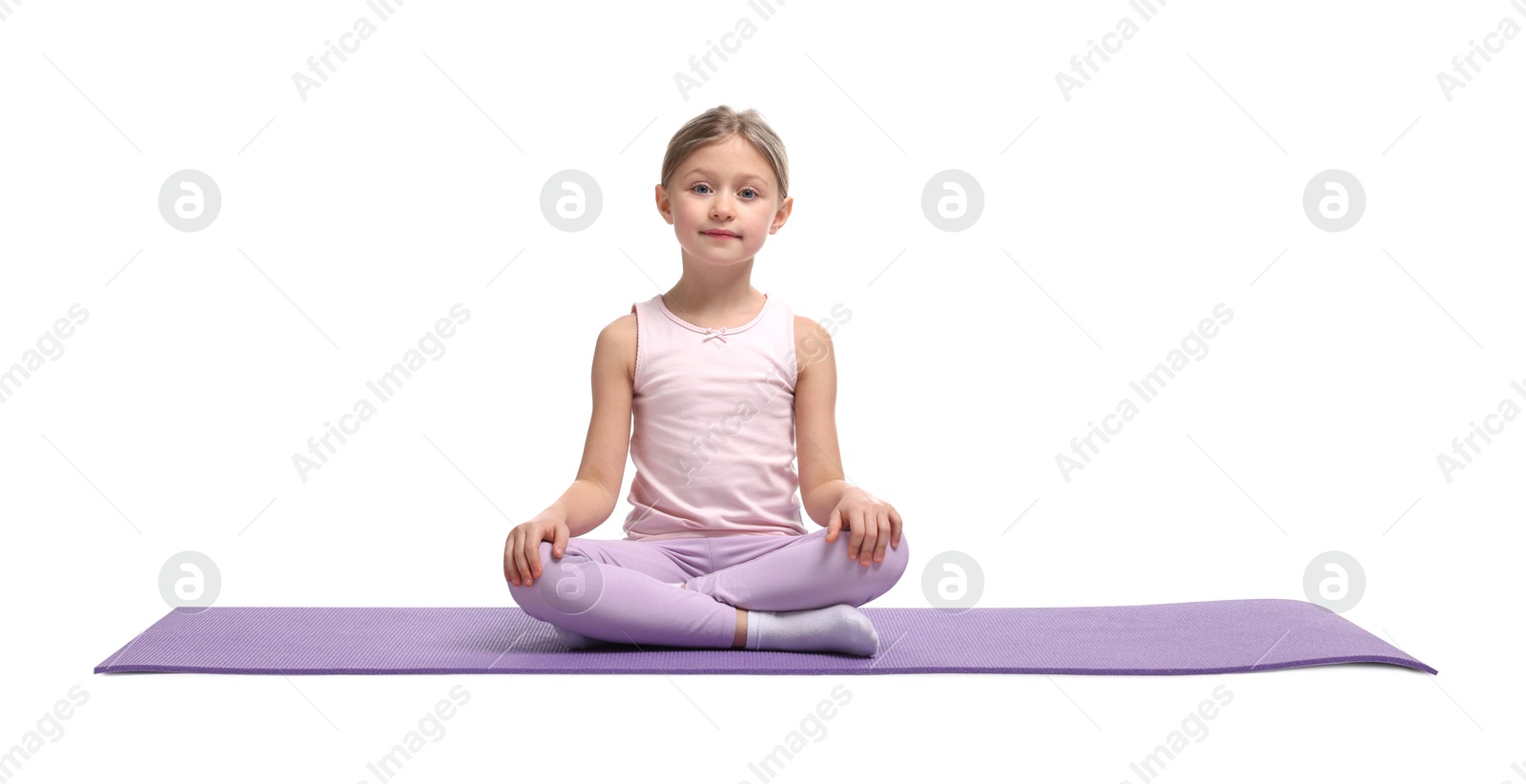 Photo of Little girl in sportswear sitting on fitness mat against white background