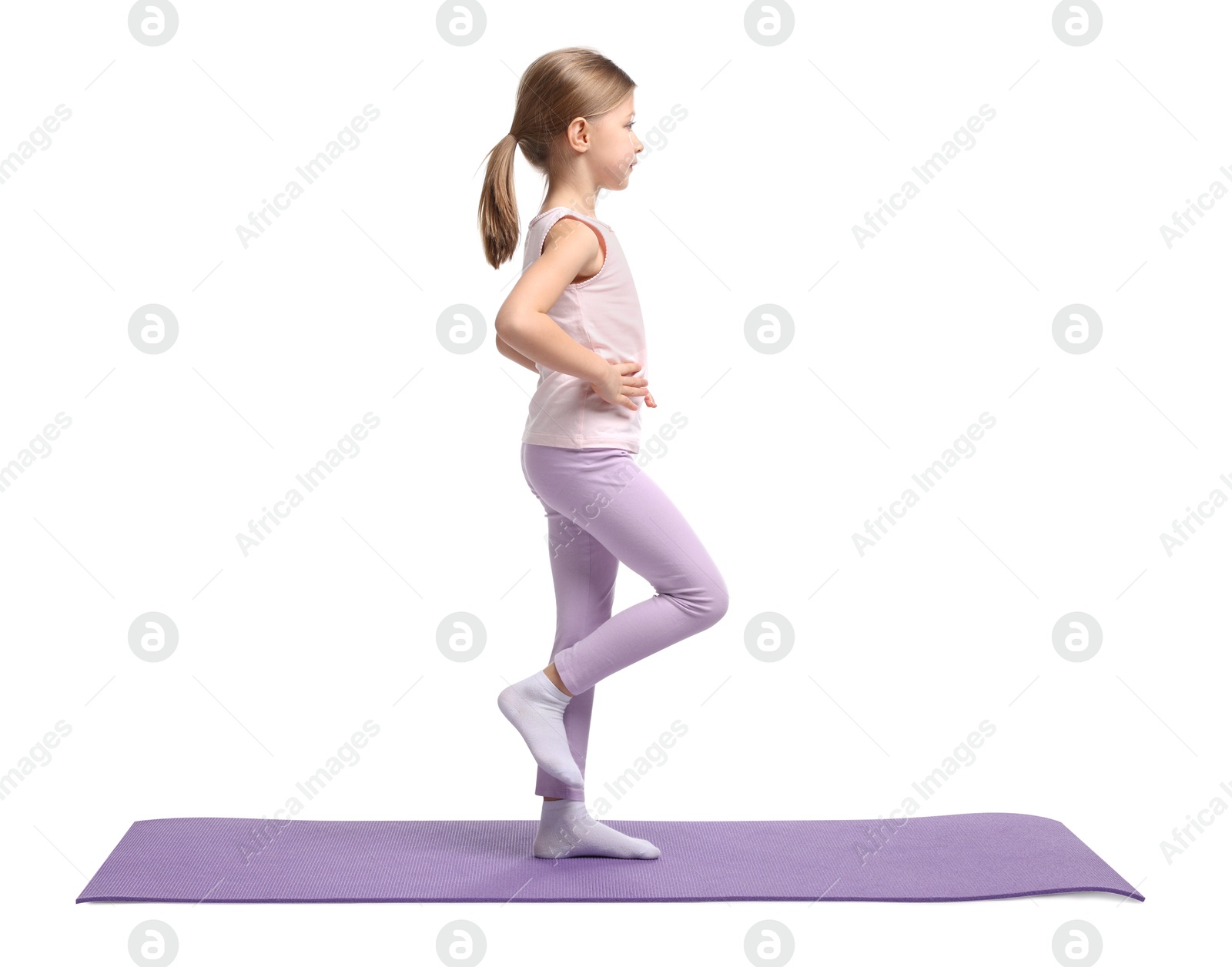 Photo of Little girl exercising on fitness mat against white background