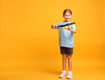 Cute little girl with tennis racket and ball on pink background, space for text