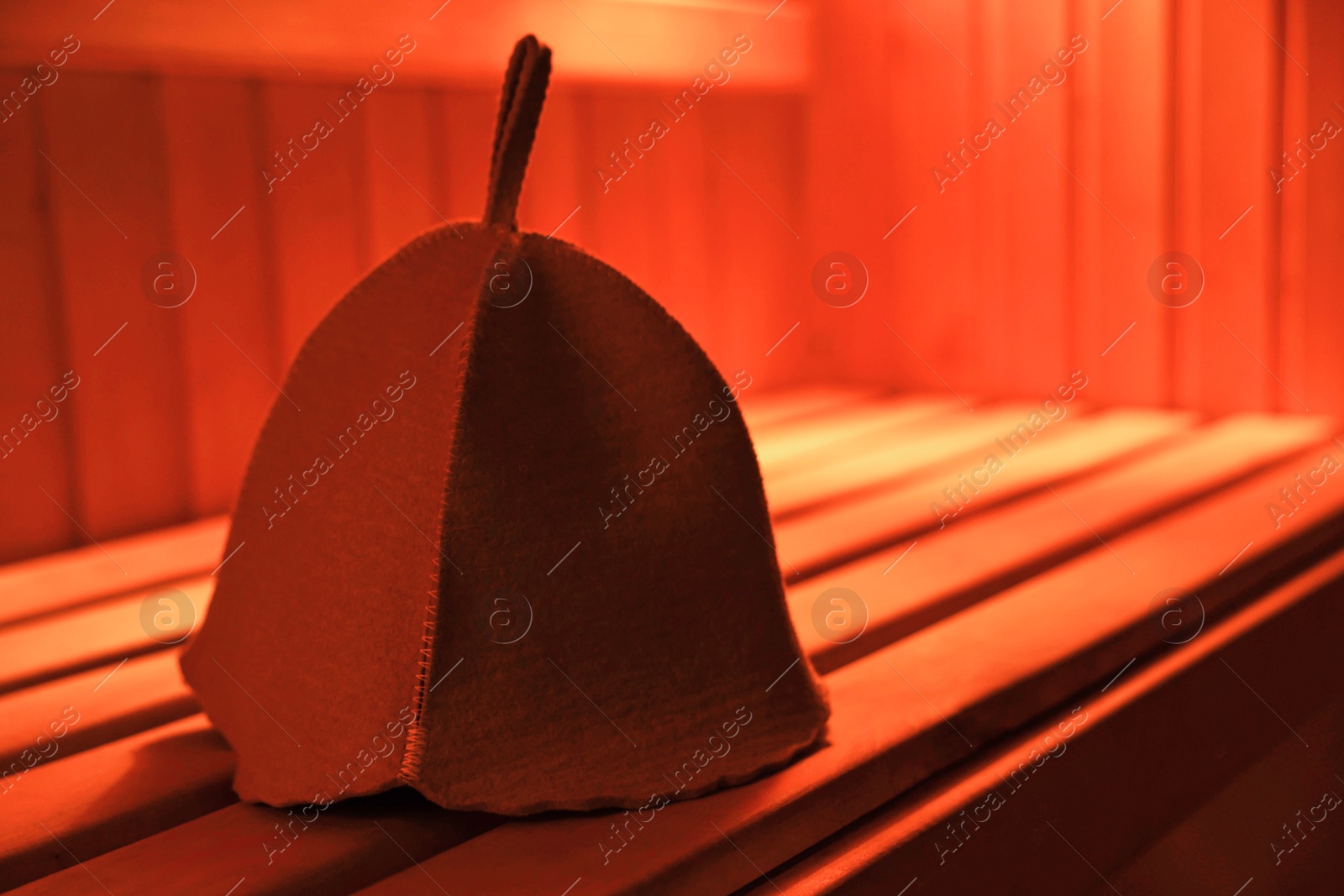 Photo of Felt wool hat on wooden bench in sauna. Space for text