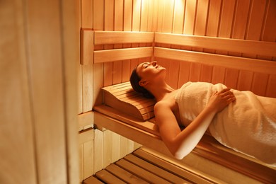 Photo of Beautiful woman relaxing on bench in sauna. Space for text