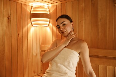 Photo of Beautiful woman wrapped in towel at sauna. Space for text